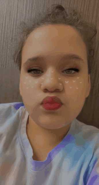 a girl with butterflies painted on her face makes a face