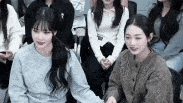 two girls are sitting next to each other in a crowd of people holding hands .