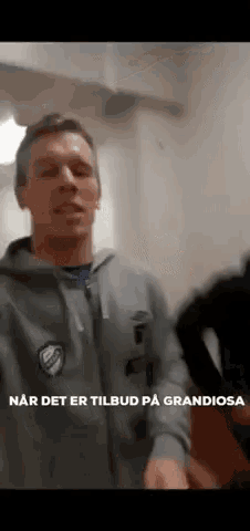 a man in a grey hoodie with the words " har det er tilbud på grandiosa " on the bottom right