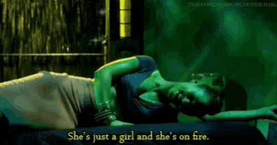 a woman is laying on a bed with a man and says she 's just a girl and she 's on fire