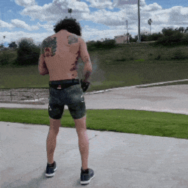 a man with a tattoo on his back is standing on a sidewalk