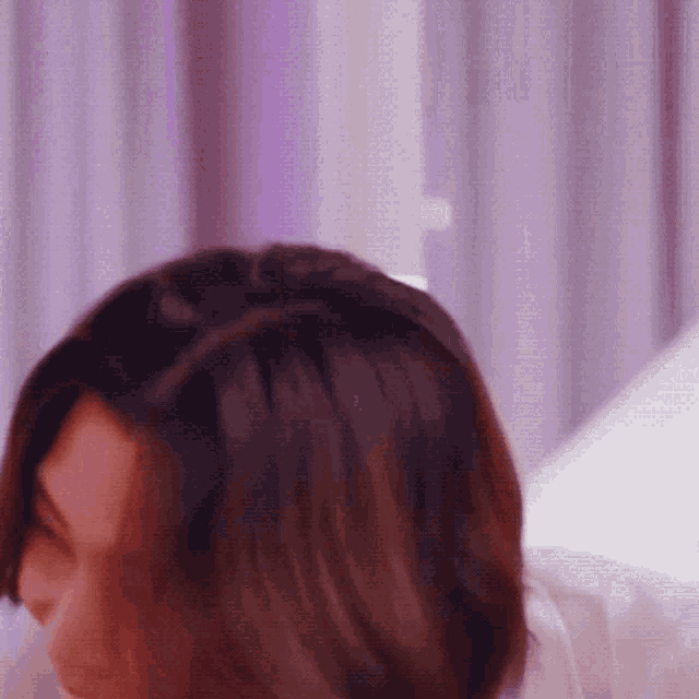 a close up of a woman 's head with purple curtains behind her .