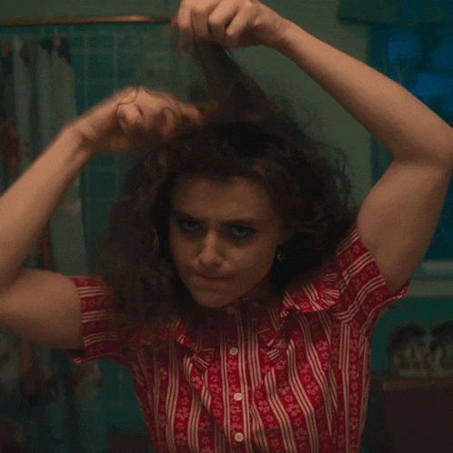 a woman in a red and white striped shirt holds her hair in her hands