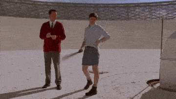 a man in a red sweater is standing next to a man in blue shorts