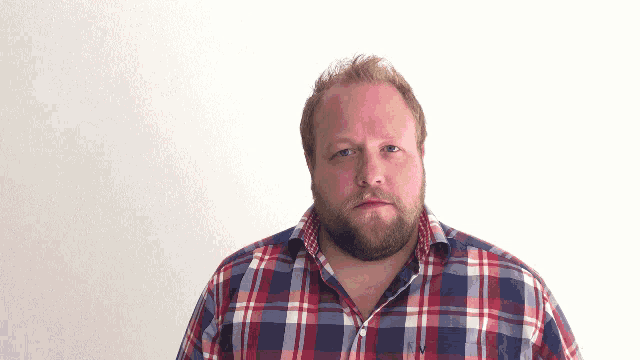 a man with a beard is wearing a plaid shirt with the letter v on the collar