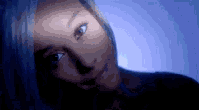 a close up of a woman 's face with a blue background and a light shining on her face .