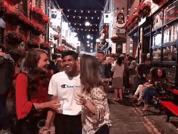 a group of people are standing on a busy street at night .