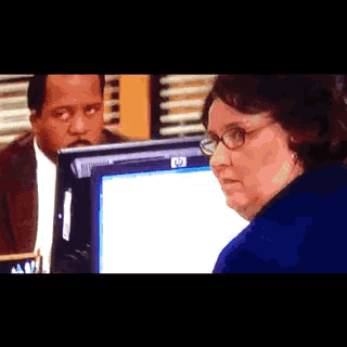 a man and a woman are looking at an hp computer