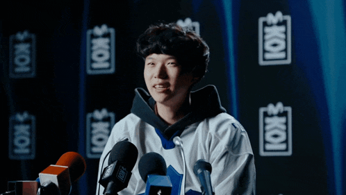 a man stands in front of a microphone with the word koi on the back