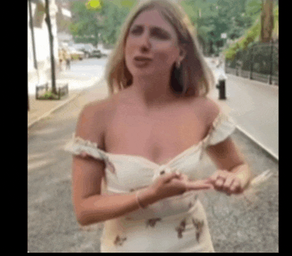 a woman in a white off the shoulder dress is standing on a sidewalk .