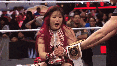 a woman in a wrestling ring with a belt that says world heavyweight champion