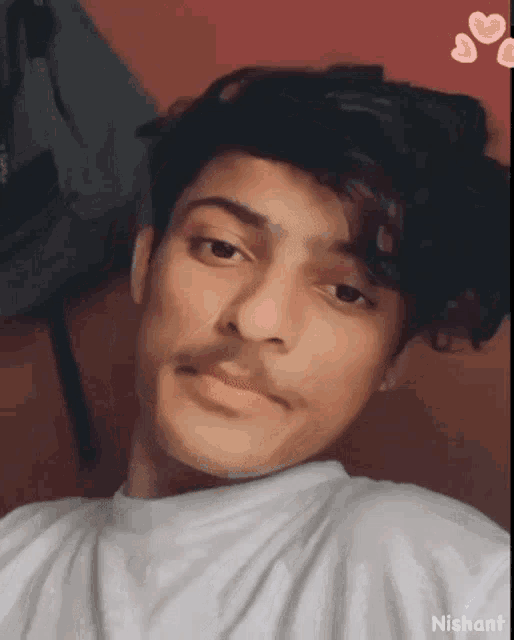 a young man with a mustache is wearing a white shirt and taking a selfie .