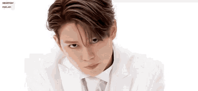 a young man wearing a white suit and tie is making a funny face .
