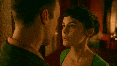 a man and a woman are looking at each other and the woman is wearing a green top