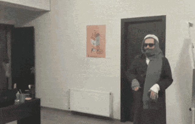 a man wearing sunglasses and a scarf is standing in a hallway