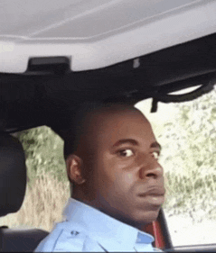 a man in a blue shirt is sitting in the back seat of a car .
