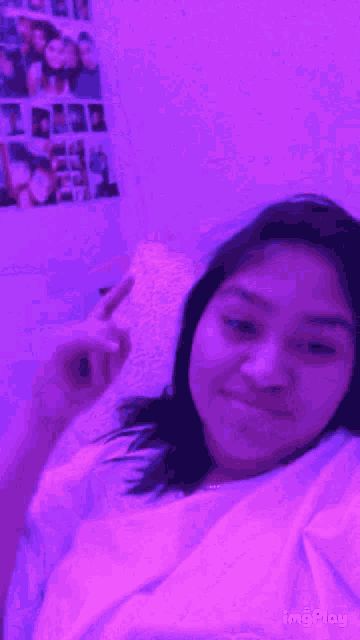a girl is laying on a bed with purple lights behind her and a purple background