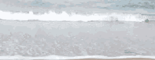 a blurred image of a beach with waves crashing on the sand .