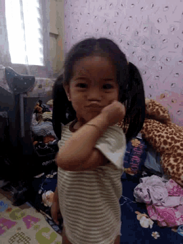 a little girl in a striped shirt is standing in front of a pile of stuffed animals including a volcano
