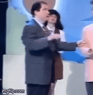 a man in a suit and tie is shaking hands with another man in a pink jacket .