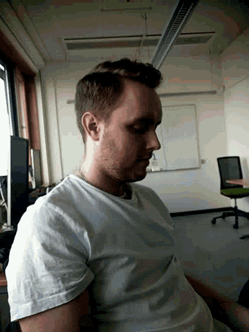 a man with his eyes closed in a room with a white board in the background