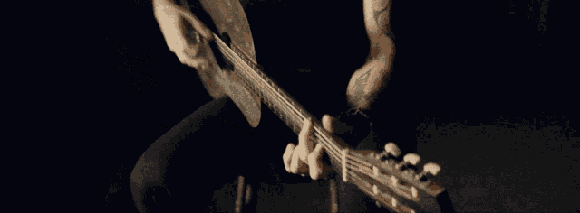 a man with a tattoo on his arm is playing a guitar in a dark room