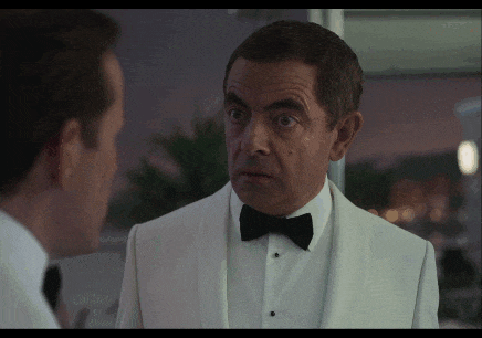 a man in a white tuxedo with a black bow tie looks at another man
