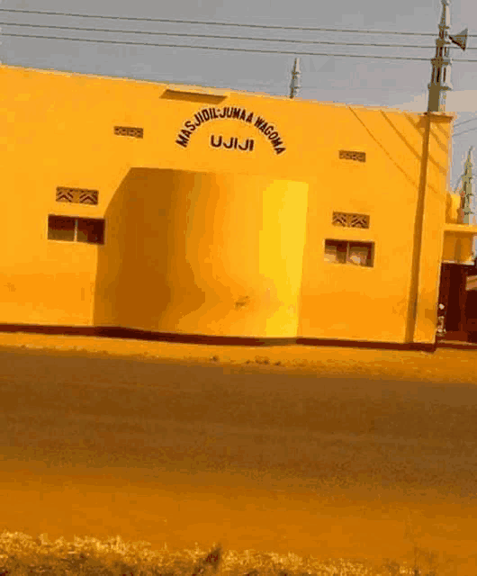 a yellow building with the words mas jidil jumaa wagoma on it
