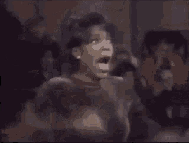 a woman is screaming with her mouth wide open in a crowd of people .