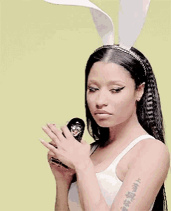 a woman wearing bunny ears is holding a russian doll in her hand .