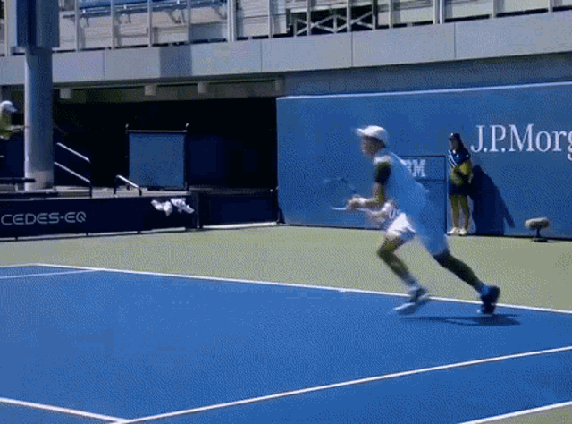 a man playing tennis on a blue court with a j.p.morgan sign behind him