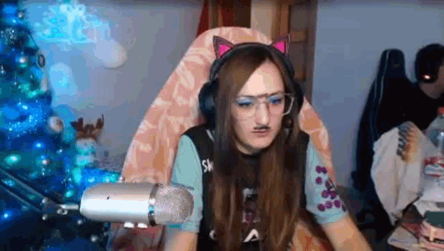 a woman wearing headphones and glasses is sitting in front of a microphone in a chair .