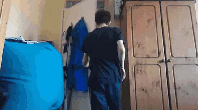 a man in a black shirt stands in front of a wooden closet