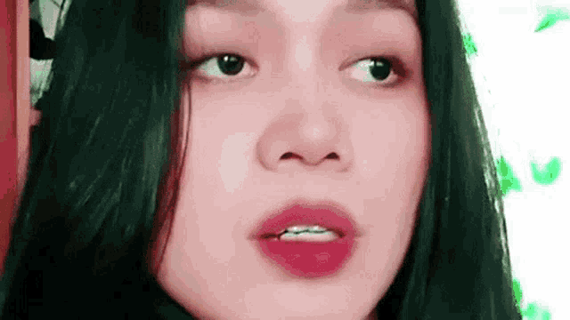 a close up of a woman 's face with green hair and red lips .