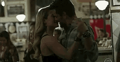 a man and a woman are kissing while dancing in a bar .