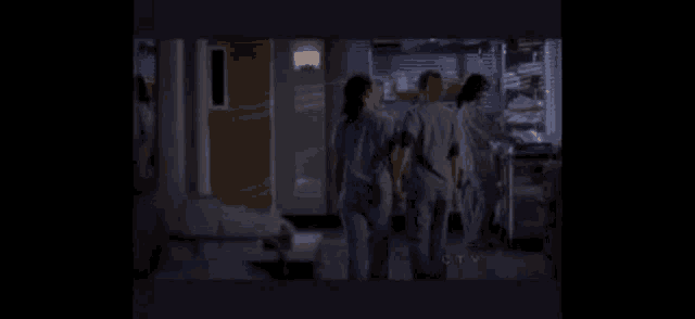 a group of doctors are walking down a hospital hallway .