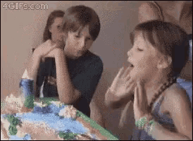 a girl blowing out a candle in front of a cake with 4gifs.com in the corner