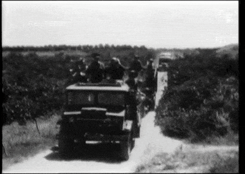 a black and white photo of a group of military vehicles driving down a road