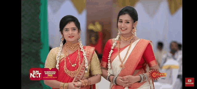two women are standing next to each other in a room and smiling for the camera .