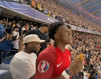 a man in a red nike shirt is standing in front of a crowd .