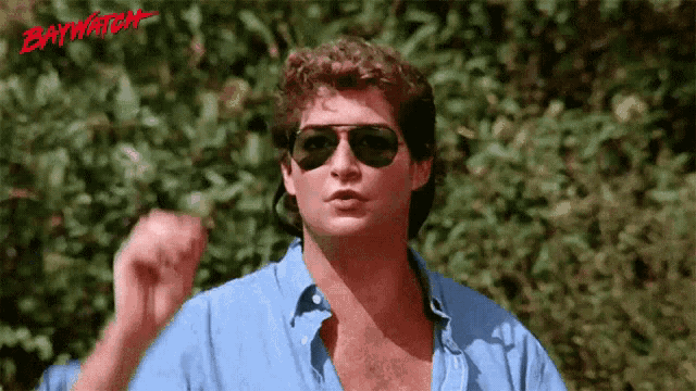 a man wearing sunglasses and a blue shirt with the word baywatch written on the bottom