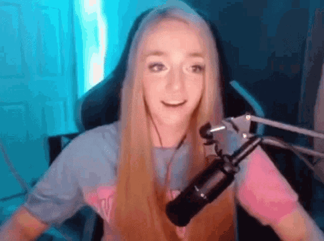 a woman with long blonde hair is sitting in front of a microphone in a room .