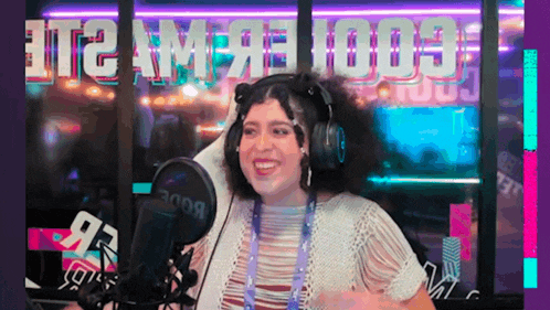 a woman wearing headphones is smiling in front of a microphone in a room .
