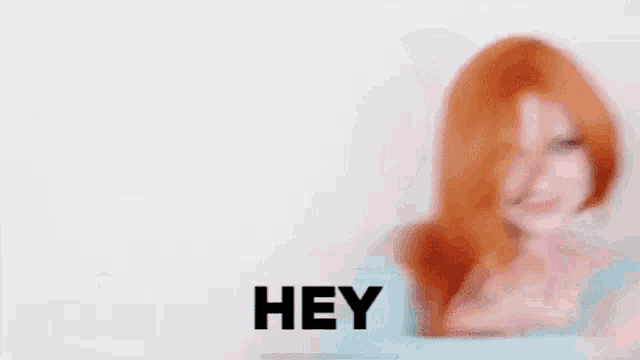 a woman with red hair is making a funny face and saying `` hey '' .