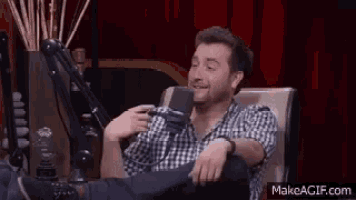 a man is sitting in front of a microphone with his feet up .