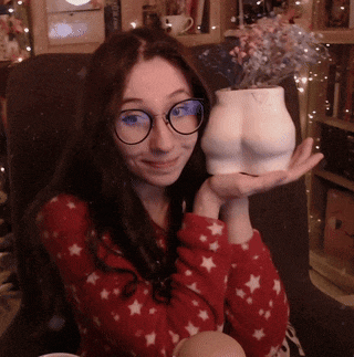 a woman wearing glasses is holding a vase in the shape of her butt