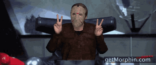 a man wearing a jason voorhees mask is giving a peace sign