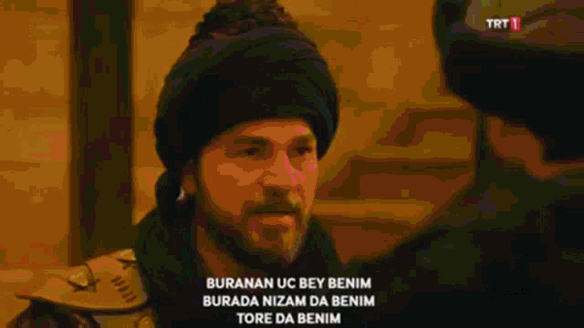 a man wearing a turban is talking to another man with trt 1 in the corner