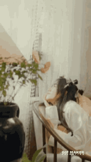 a woman is sitting in a chair looking out a window