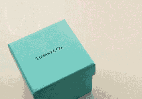 a blue box from tiffany & co. with pink hearts coming out of it